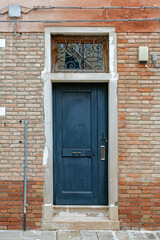 Old dark green entrance door outside on a building with brick wall facade
