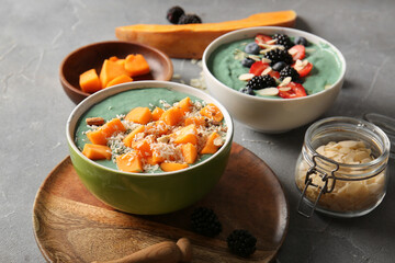Bowls of tasty spirulina smoothie on grey grunge background