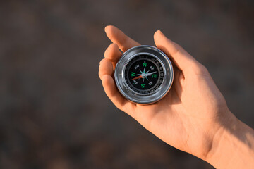 Woman with compass in forest at sunset, closeup