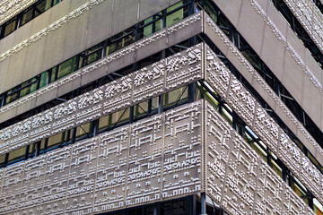 Modern building facade features intricate, perforated metal panels with geometric patterns, reflecting urban sophistication. Sleek design with large windows captures contemporary architecture