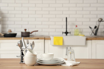 Different clean dishes on wooden table in stylish kitchen