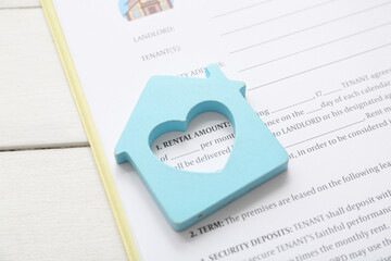 Blank house rental agreement with figure on white wooden background, closeup