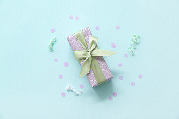 Lilac gift box with serpentine and confetti on blue background