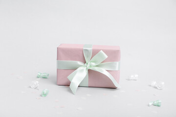 Pink gift box with serpentine and confetti on grey background