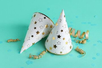 Party hats with serpentine and confetti on turquoise background