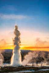 Strokkur geyser erupts at sunrise in Iceland. Strokkur is one of Iceland's most famous geysers, erupting once every 6 to 10 minutes. Its column can reach 40 m high.