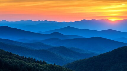 Obraz premium Blue layered mountains at sunset with orange and yellow sky in the background landscape scenery view