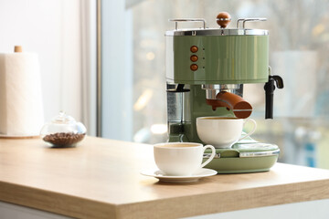 Coffee machine with cups of espresso on table in kitchen, closeup