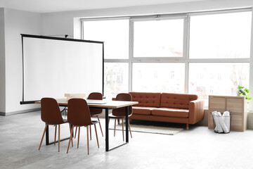Interior of conference hall with projector screen, sofa and table