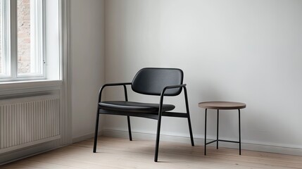 Fototapeta premium Corner with retro black armchair and round side table beside white painted wall