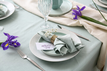 Beautiful table setting for Mother's Day celebration with greeting card and iris flowers, closeup