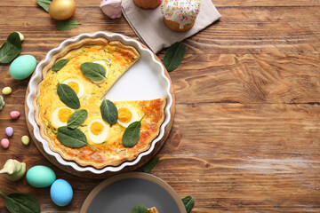 Cut Easter egg tart with spinach leaves and sweet cake on wooden background