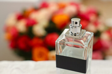 Bottle of perfume against beautiful roses, closeup. Space for text