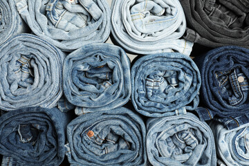 Different stylish rolled jeans as background, top view