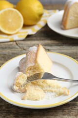 Piece of delicious lemon cake and fork on wooden table, closeup