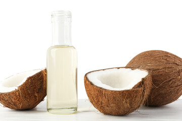 Organic coconut cooking oil in glass bottle and fresh fruits on wooden table against white...