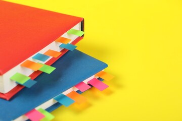 Books with colorful tabs on yellow background, closeup. Space for text