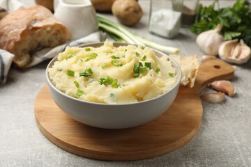 Delicious mashed potato with green onions served on grey table, closeup
