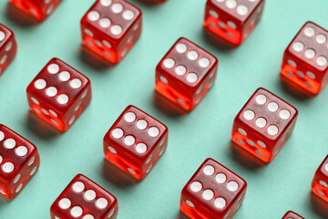 Red game dices on turquoise background, closeup