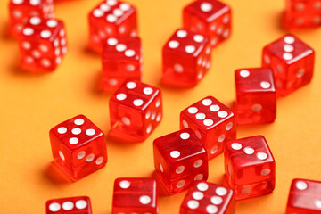 Red game dices on orange background, closeup
