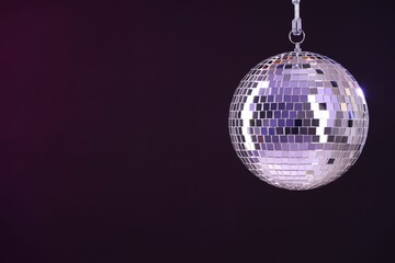 Shiny disco ball on dark purple background, space for text