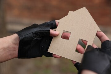 Homeless man with carton house figure outdoors, closeup