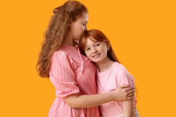Beautiful young woman hugging her cute daughter on yellow background. Mother's Day celebration