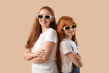 Beautiful young woman with her cute daughter in stylish sunglasses on brown background. Mother's...