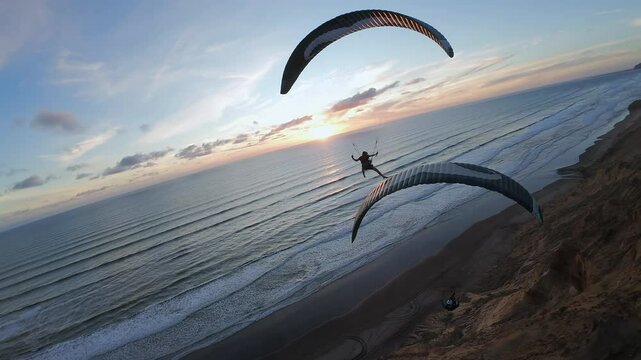 Two paragliders friends soaring along New Zealand&rsquo;s coastline at sunset. Aerial footage capturing adventure, speed, and golden hour beauty.