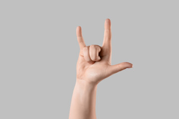 Male hand showing "I LOVE YOU" gesture on light background
