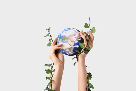 Female hands with plant branches and paper Earth on white background. Ecology concept