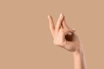 Female hand snapping fingers on beige background