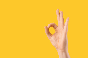 Male hand showing OK on yellow background