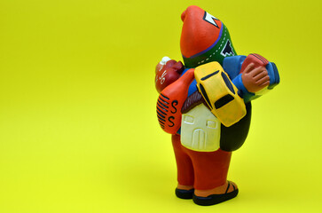 View of the back of a Peruvian Ekeko, symbol of good fortune, showcased on a vibrant yellow backdrop