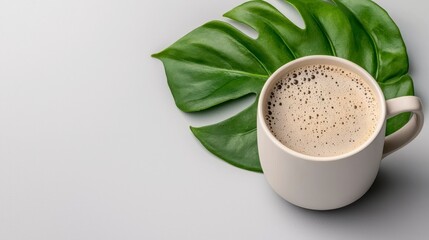 Off White Coffee Mug and Green Tropical Leaf on Gray Surface