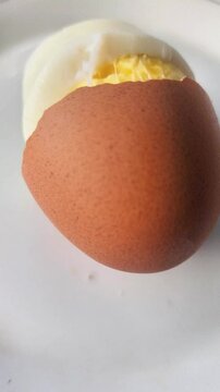 Peeled chicken eggs, showing the contents are yellow and white, on a white ceramic plate with protein inside