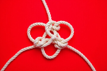 white rope tied in a knot on a red background