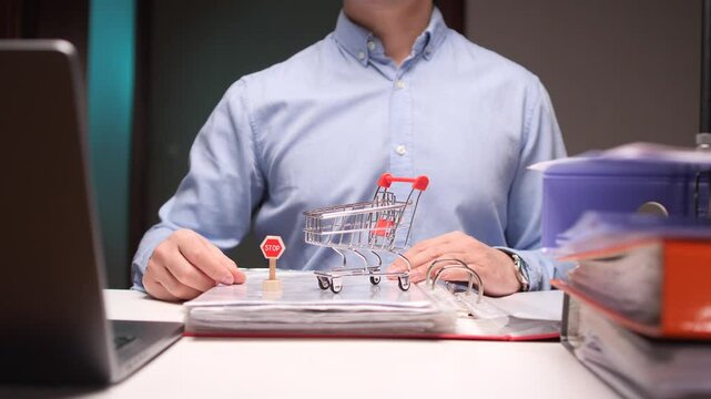 Office worker stopping online shopping impulse with miniature stop sign