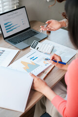 Professionals reviewing financial reports and charts, discussing strategies at a modern office workspace.