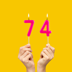 Birthday number 74 - Hands holding fuchsia colored candles