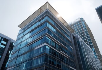 Obraz premium Modern glass office building with reflective windows under a bright sky.