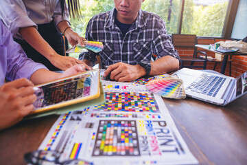 Team graphic designer checking print quality of media graphics proof print and color guides in...
