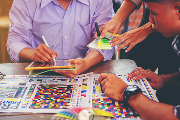 Team graphic designer checking print quality of media graphics proof print and color guides in...