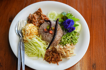 Close up shot of Thai shrimp paste fried rice with shallot, sweet barbeque pork, fried egg, vegetable and spicy chili.
