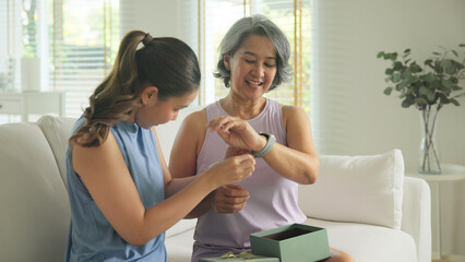 Young adult child give gift AI smart watch IOT app to mature middle age old mum. Love health care...