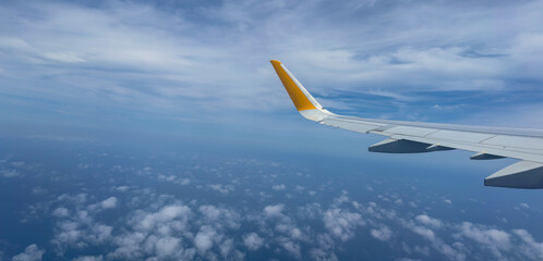 A close up view of an airplane wing with a cloudy sky in the background. Conveys a sense of travel, adventure, and freedom, perfect for aviation and tourism