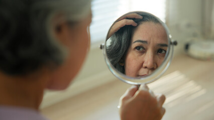 Asia adult people middle age old woman look at mirror dry skin face hand touch neck cheek stress...
