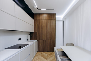 A kitchen with white cabinets, stove top oven, table and chairs