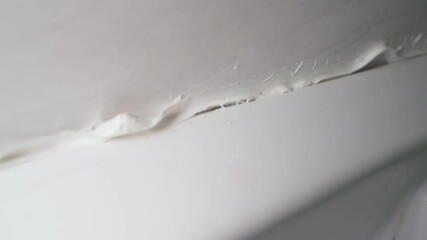 Smooth camera movement close-up of poor quality white sealant. Sealing joints against moisture ingress