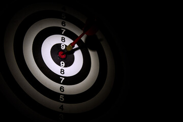 Dart arrow hitting in the target center of dartboard,Arrow on a black background